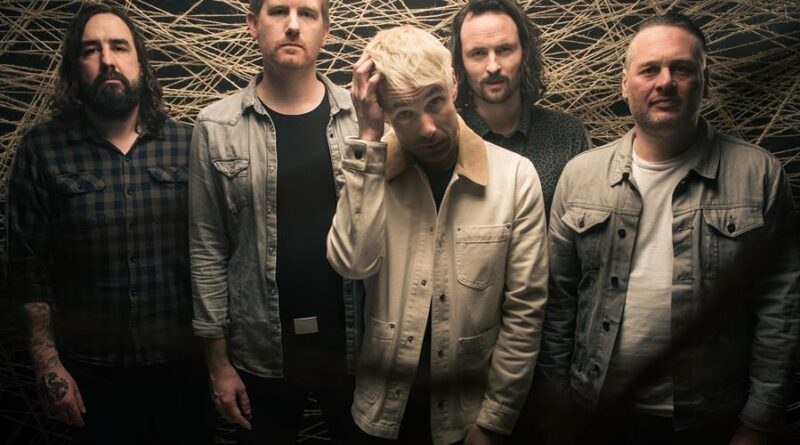 5 men stand and pose for a band photo